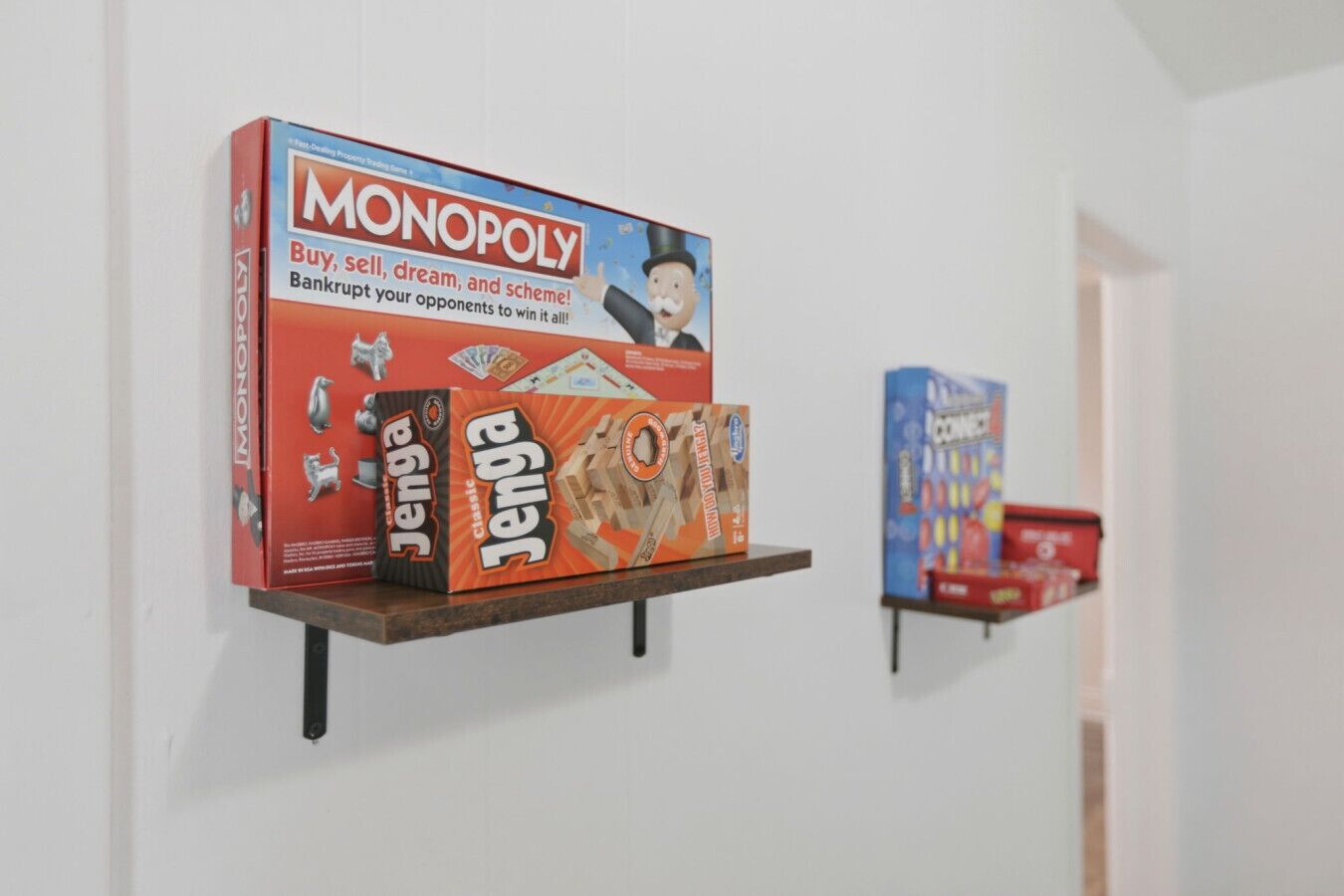 Seinälle kiinnitetty hylly, jossa on esillä lautapelejä, kuten Monopoly ja Jenga.
