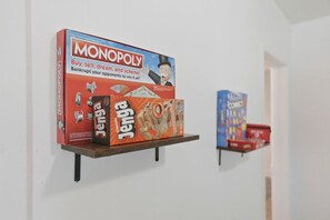 Una exhibición de juegos de mesa, incluyendo Monopoly y Jenga, sobre una estantería de pared.