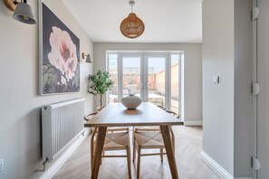 A dining area with a table, chairs, a vase, and a large flower painting on the wall. - Beautifully renovated cottage in a fantastic location with free parking (Stratford-upon-Avon)