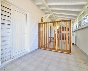 A covered outdoor area with a wooden partition, a white door, and a tiled floor. - Outbuilding in villa with sea view near Grand Bourg (Grand-Bourg)