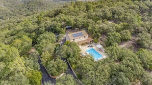 A house with a swimming pool surrounded by dense forest, solar panels on the roof, and a clear view of the surrounding hills. - Villa Sur la Colline by Villa Plus (Les Adrets-de-l'Estérel)