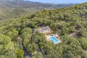 Ein Haus mit Swimmingpool, umgeben von dichtem Wald, Solaranlagen auf dem Dach und freiem Blick auf die umliegenden Hügel.