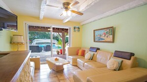 A living room with a sofa, a coffee table, a TV, and a ceiling fan. - Villa Sur la Colline by Villa Plus (Les Adrets-de-l'Estérel)