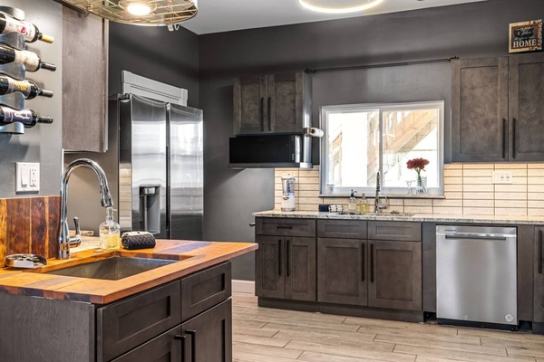 Wall-mounted wine rack, butcher block island sink, French door fridge, and dishwasher — this kitchen has everything going for it.