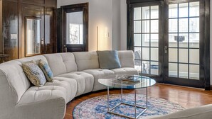 Una sala de estar con un sofá modular, una mesa de centro de vidrio y una alfombra estampada.