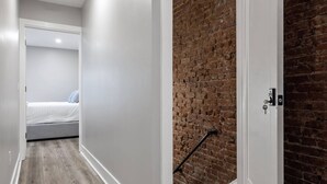 Un pasillo con una cama, una pared de ladrillo y una puerta con cerradura.