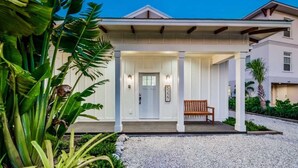 A house with a covered porch, a door, and a bench. - Bahama Mama | Tropical Retreat on Siesta Key (Siesta Key)