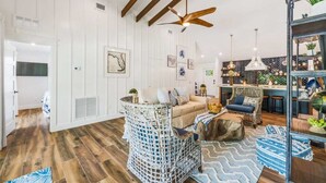 A spacious living area with a high ceiling, a central seating area with a sofa and chairs, a kitchen area with bar stools, and a dining table. - Bahama Mama | Tropical Retreat on Siesta Key (Siesta Key)