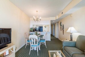 Ein Hotelzimmer mit Fernseher, einem Essbereich mit Stühlen und Tisch, einer Couch und einer Küche im Hintergrund.