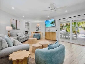 Ein modernes Wohnzimmer mit grauem Sofa, blauem Sessel und einem Fernseher an der Wand.