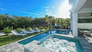 Une piscine avec des chaises longues, un jacuzzi et une vue sur la verdure.