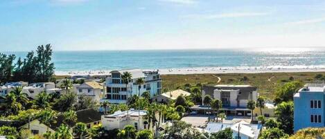 A coastal residential area with modern houses, a beach, and a clear view of the ocean.