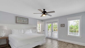 Ein Schlafzimmer mit Bett, Deckenventilator, Nachttisch und Fenster mit Jalousien.