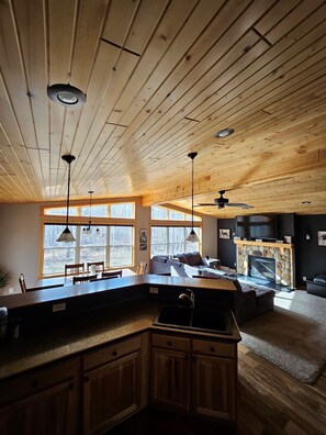 Une cuisine spacieuse avec des meubles en bois, un coin repas avec une table et des chaises, et un salon avec un canapé et une cheminée.