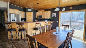 A spacious kitchen with wooden cabinets, a central island, and a dining area with a large wooden table and chairs. - Oasis in Saginaw - Pvt Pool, Hot Tub (Saginaw)