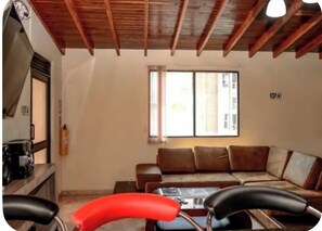 Ein Wohnzimmer mit Holzboden, einem braunen Ledersofa, einem Couchtisch und einem roten Sessel.