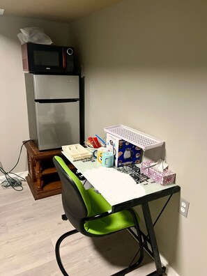 Eine kompakte Küchenzeile mit einer Mikrowelle, einem Kühlschrank und einem kleinen Tisch mit diversen Gegenständen.