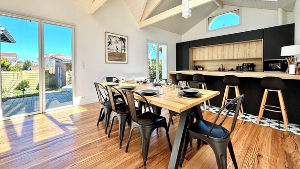 A modern kitchen with a wooden countertop, black chairs, and a dining table set for six. - Renovated villa in the heart of Arcachon + outbuilding (Arcachon)