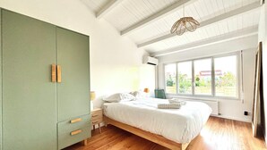 A bedroom with a bed, a wardrobe, a window, and a ceiling light. - Renovated villa in the heart of Arcachon + outbuilding (Arcachon)