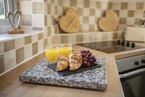 A breakfast setup with croissants, grapes, and orange juice on a granite countertop. - Lyke Wake Cottage, Swainby, Yorkshire (Northallerton)