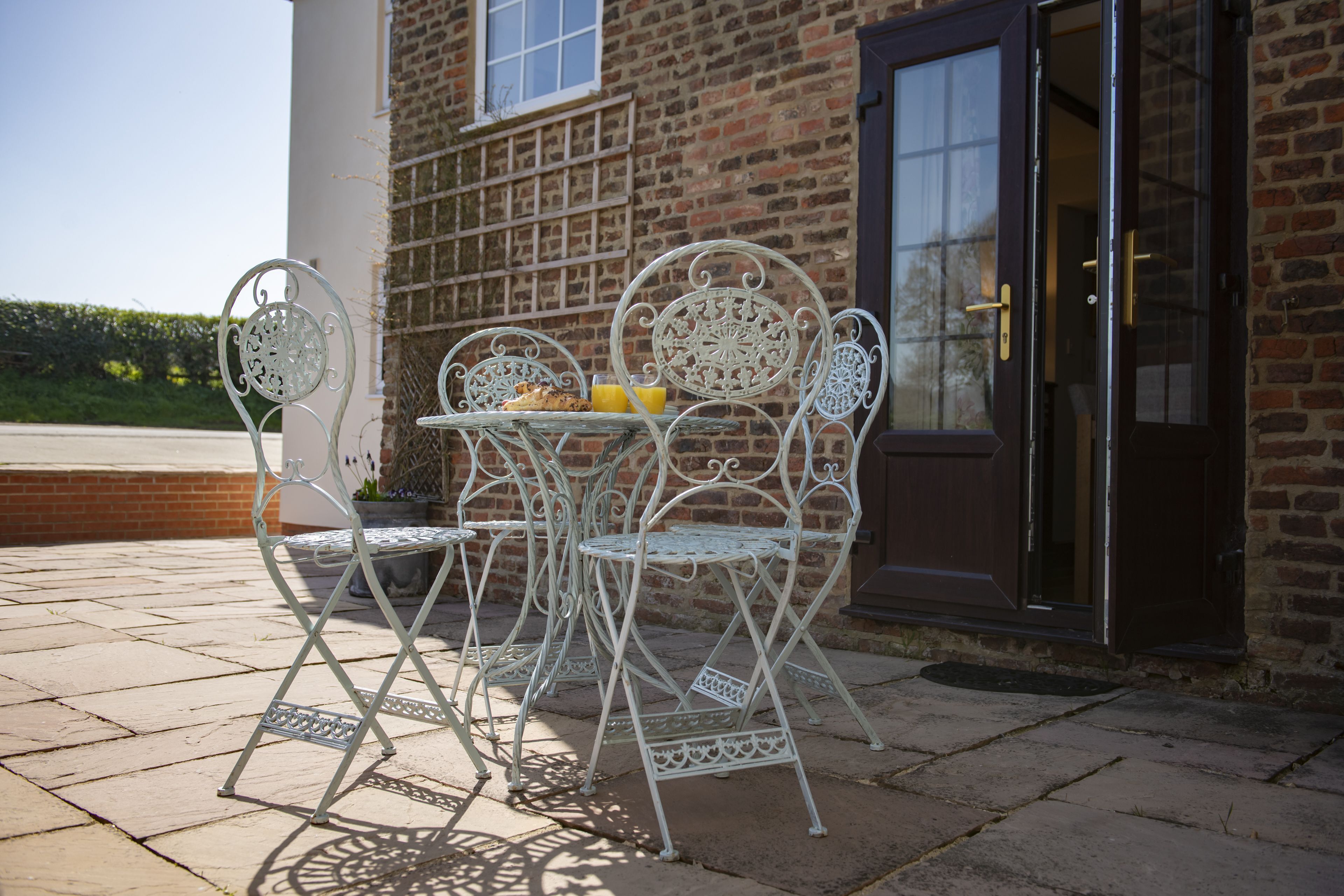 A patio with metal chairs and a table, a brick wall, and a door.