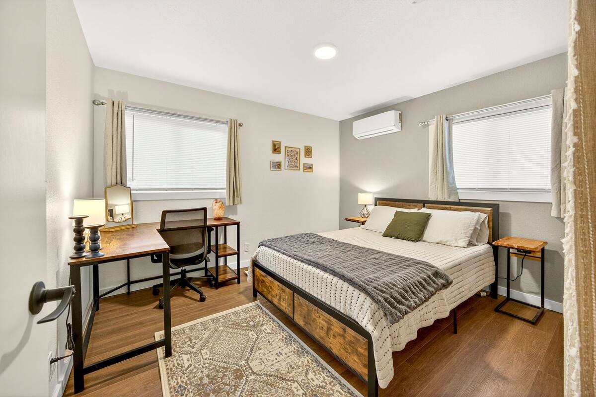 Un dormitorio con cama, escritorio, silla y alfombra.