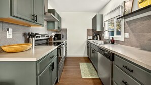 Une cuisine moderne avec des meubles gris, des appareils en acier inoxydable et un tapis vert.