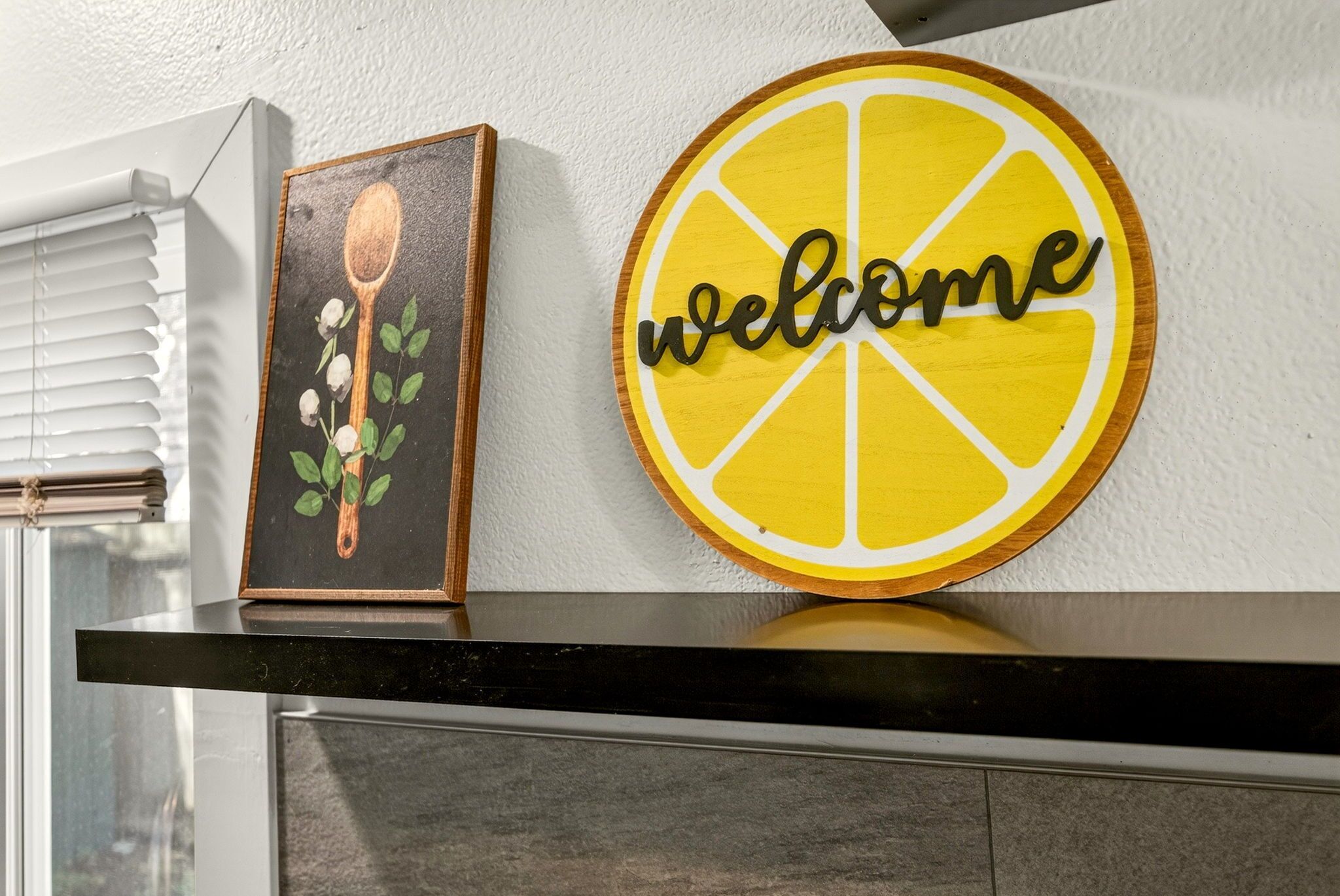 A kitchen counter with a framed picture and a 'welcome' sign.