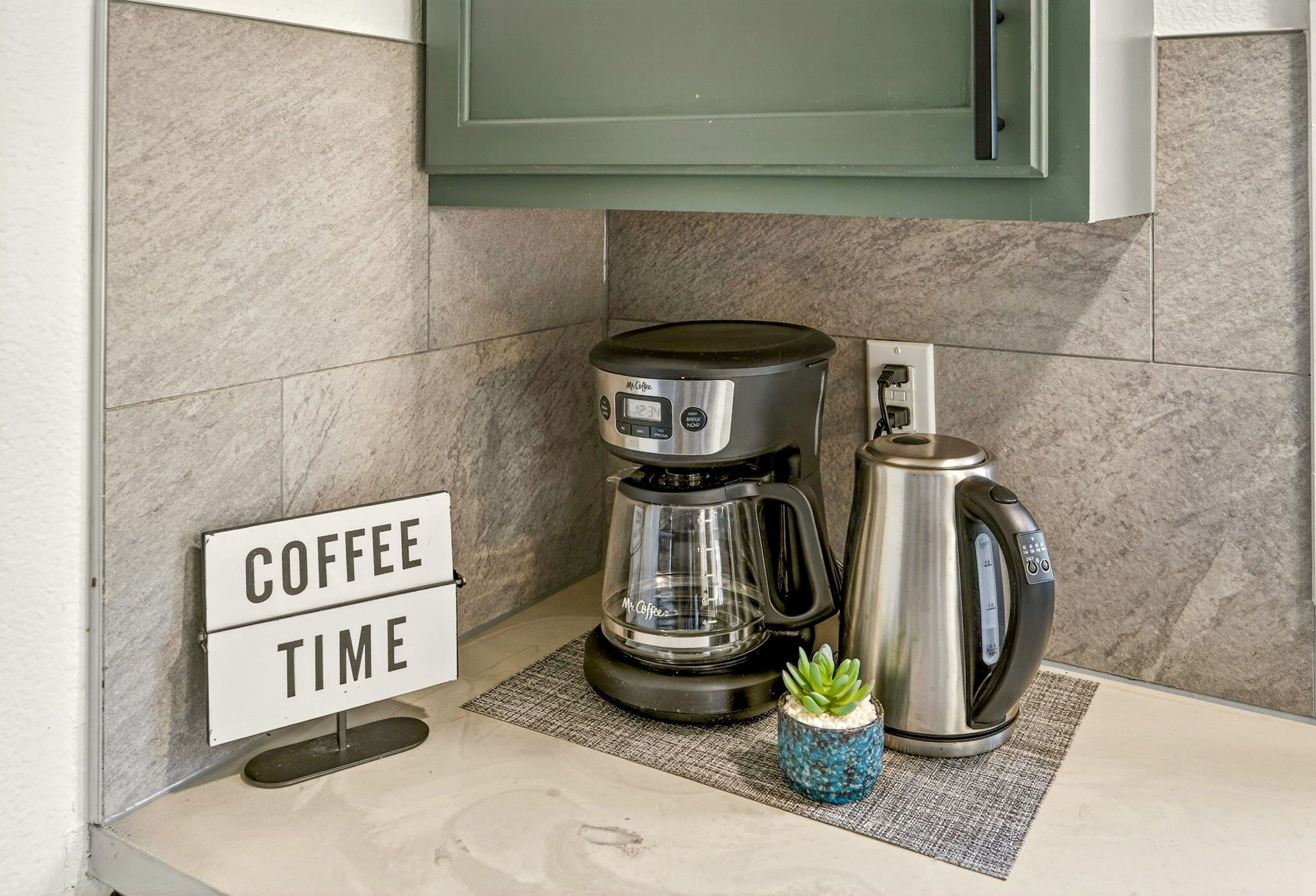 A kitchen with a coffee maker, a kettle, and a sign that reads 'COFFEE TIME'.