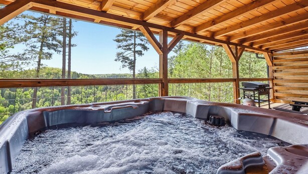 Un jacuzzi con techo de madera y vista a árboles.
