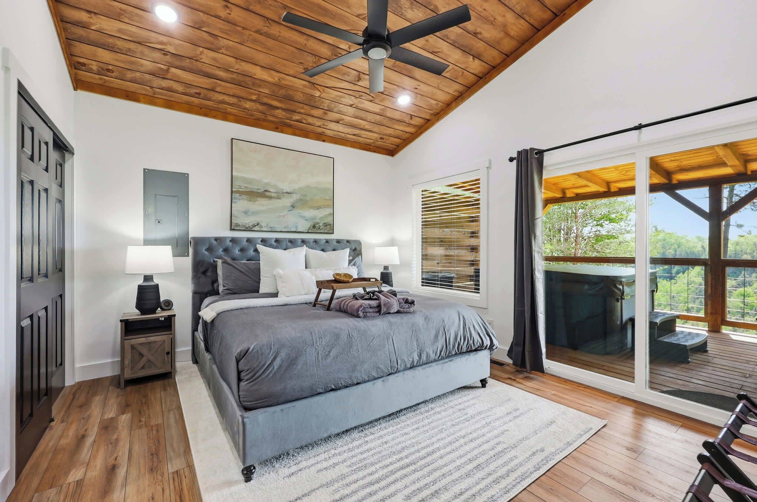 Ein Schlafzimmer mit einem großen Bett, Holzboden und einer Schiebetür zu einer Terrasse.