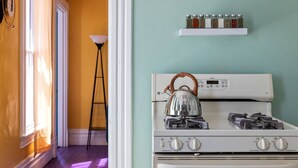 A kitchen with a white stove, a kettle, and a shelf with spice jars. - Retro 1BR Flat in the Heart of East Liberty | Queen Bed | Longer Stays Welcome (Pittsburgh)