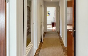 A hallway with a carpeted floor, wooden doors, and a view into a room with a bed and a window. - Lovely home in Rørvig with WiFi (Rørvig)