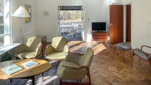 Un salon équipé d’un téléviseur, de meubles en bois et offrant une vue à travers une porte vitrée.