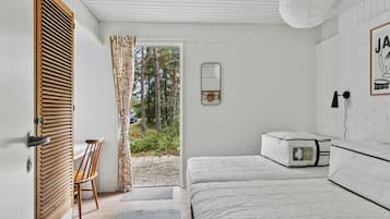 Une chambre à coucher comprenant un lit, une chaise, une table de chevet, un miroir et une porte donnant sur un espace extérieur.