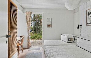 A bedroom with a bed, a chair, a bedside table, a mirror, and a door leading to an outdoor area. - 3 bedroom cozy home in Højby (Højby)