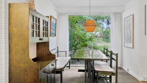 A dining area with a table, chairs, and a hanging light fixture.