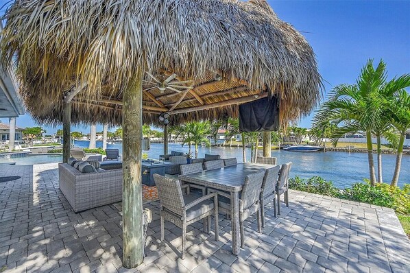 A covered outdoor seating area with wicker furniture, a thatched roof, and a view of a body of water. - waterfront corner lot (Pompano Beach)