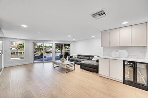 A modern living room with a sofa, coffee table, and a view of a pool. - waterfront corner lot (Pompano Beach)