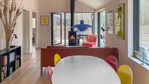 Ein modernes Interieur mit einer zentralen Sitzecke, einem Kamin und Blick durch große Fenster.