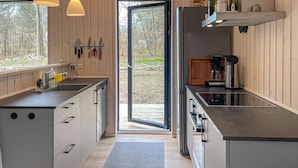 Eine moderne Küche mit großem Fenster, einem eingebauten Geschirrspüler und einer Kaffeemaschine.
