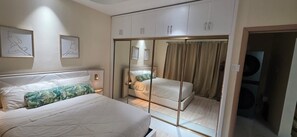 A bedroom with two beds, a wardrobe, and a mirror. - Coastal Retreat. Beach life. Luxury 1 BR apartment at the Paradisiac Beach Club. (Richmond Estate)