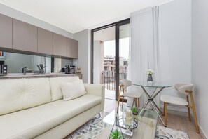 Ein modernes Wohnzimmer mit einer Couch, einem Glastisch und einem Essbereich mit Stühlen.
