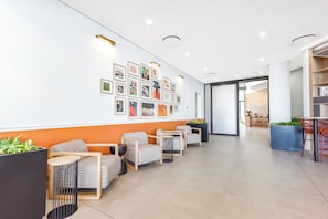 Ein Empfangsbereich mit einer Wand voller gerahmter Kunstwerke, Sitzgelegenheiten und einem Empfangstresen.