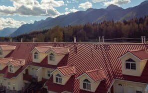 Rivissä punakattoisia taloja, joiden valkoiset seinät erottuvat vuorten ja puiden muodostamaa taustaa vasten.