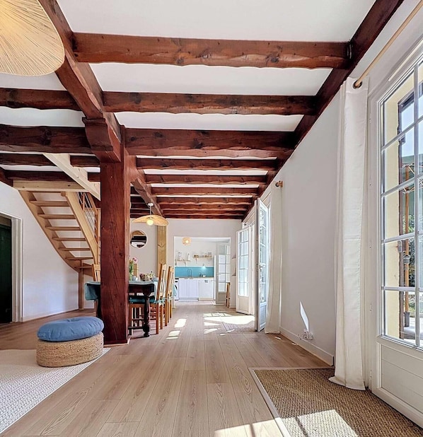 Ein geräumiger Korridor mit Holzbalken, einer Treppe, einem Essbereich und großen Fenstern.