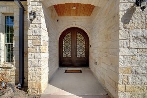 A stone building entrance with a wooden door and a window to the left.