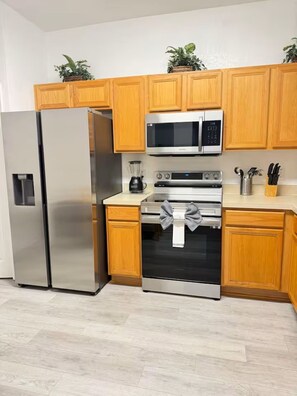 A modern kitchen with stainless steel appliances, wooden cabinets, and a countertop with a knife block and utensils. - 615 Resort Villa Close to Disney World (Davenport)