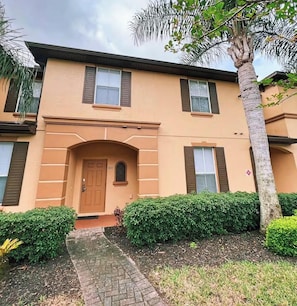 A two-story building with a brown door, windows with shutters, and a paved entrance. - 615 Resort Villa Close to Disney World (Davenport)