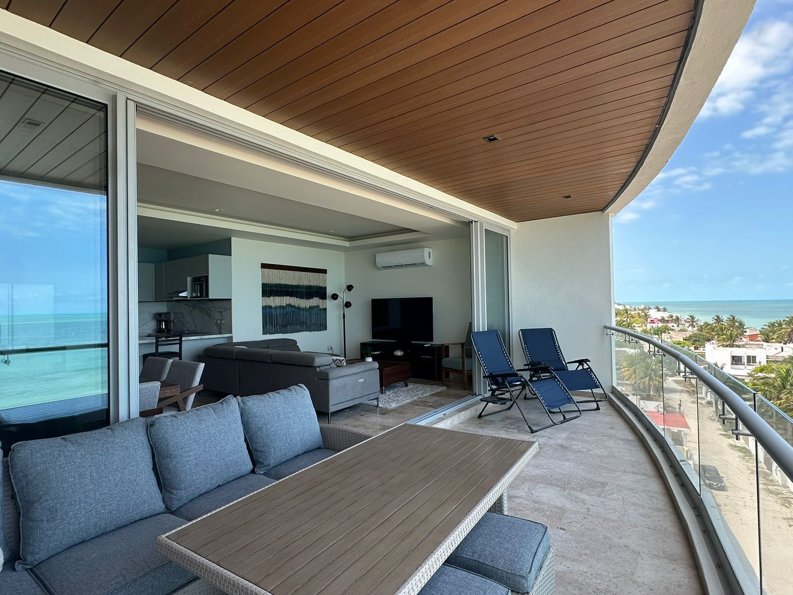 Ein Balkon mit Holzboden, einer Couch, einem Tisch und zwei Stühlen.